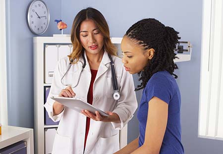 African American patient explaining issues to Asian doctor using tablet doctor with patient